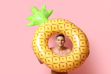 Pembe arka planda şişme yüzüğü olan çekici bir genç adam.