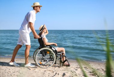 Deniz tatil köyünde fiziksel engelli genç adam ve kız arkadaşı.