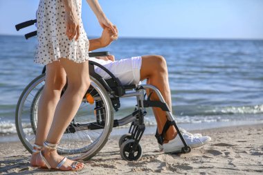 Deniz tatil köyünde fiziksel engelli genç kadın ve erkek arkadaşı.