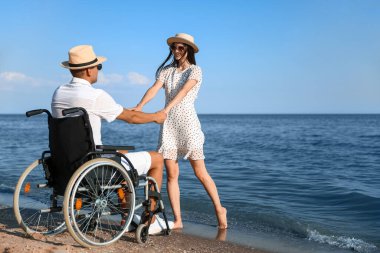 Fiziksel engelli genç bir adam ve deniz kenarındaki kız arkadaşı.