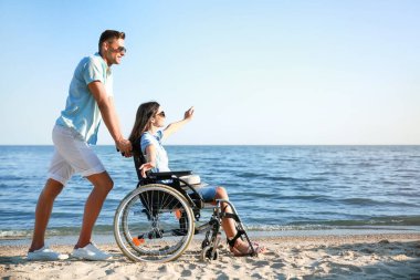 Young woman with physical disability and her boyfriend at sea resort clipart
