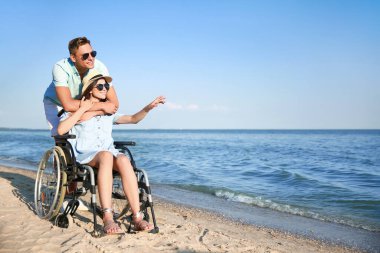 Fiziksel engelli mutlu bir kadın ve deniz kıyısındaki erkek arkadaşı.