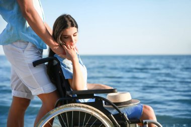 Fiziksel engelli genç bir kadın ve deniz kenarındaki erkek arkadaşı.