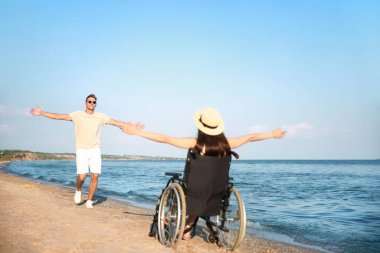 Fiziksel engelli mutlu bir kadın ve deniz kıyısındaki erkek arkadaşı.