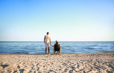 Fiziksel engelli genç bir kadın ve deniz kenarındaki erkek arkadaşı.