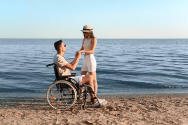 Fiziksel engelli genç bir adam ve deniz kenarındaki kız arkadaşı.