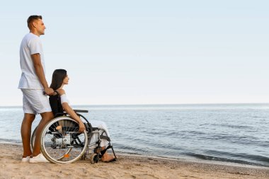 Fiziksel engelli genç bir kadın ve deniz kenarındaki erkek arkadaşı.