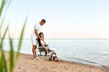 Fiziksel engelli genç bir kadın ve deniz kenarındaki erkek arkadaşı.