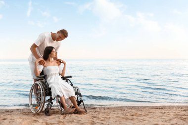 Fiziksel engelli genç bir kadın ve deniz kenarındaki erkek arkadaşı.