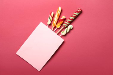 Renk arkaplanı üzerinde boş kart ve tatlı lolipoplar olan kompozisyon