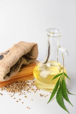 Kenevir yağı ve beyaz arka planda tohumları olan torba süprüntüsü