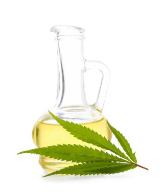 Beyaz arka planda cam kenevir yağı ve yaprağı sürahisi