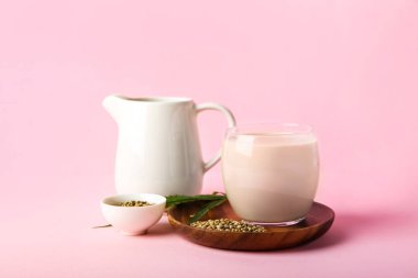 Pembe arka planda kenevir sütü ve çekirdekli kompozisyon