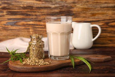 Ahşap arka planda tohumlu kenevir sütü ve şişe.