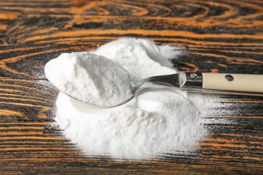 Ahşap arka planda kabartma tozu ve kaşık yığını