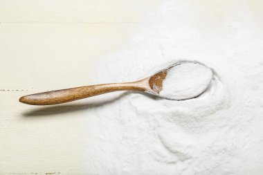 Beyaz ahşap arka planda kabartma tozu ve kaşık yığını