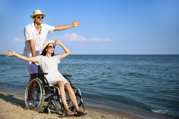 Fiziksel engelli mutlu bir kadın ve deniz kıyısındaki erkek arkadaşı.