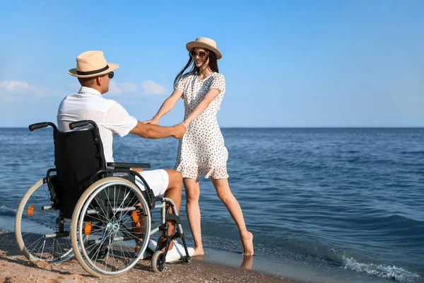 Fiziksel engelli genç bir adam ve deniz kenarındaki kız arkadaşı.