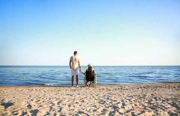 Fiziksel engelli genç bir kadın ve deniz kenarındaki erkek arkadaşı.