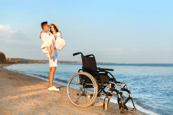 Happy young couple with wheelchair at sea resort