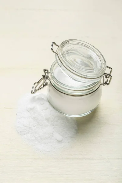 Jar with baking soda on white wooden background