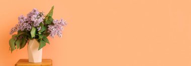 Masanın üzerinde güzel bir demet leylak olan vazo, metin için alanı olan renk arkaplanına karşı