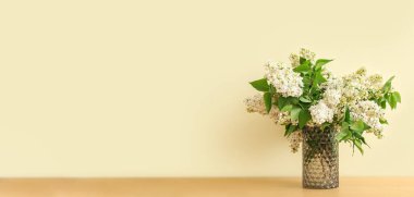 Masada açık renk arkaplan ve metin için alanı olan güzel beyaz leylak buketli vazo