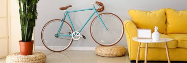 Sarı kanepeli ve bisikletli aydınlık oturma odasının içi. Tasarım için pankart