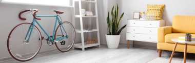Interior of light living room with bicycle, chest of drawers and armchair. Banner for design