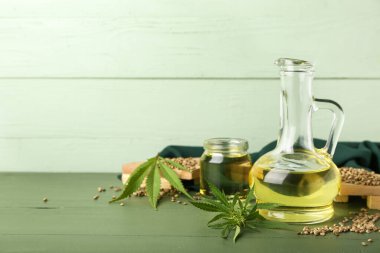 Kenevir yağı, tohum ve yapraklı süsleme renkli ahşap arka planda