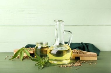 Kenevir yağı, tohum ve yapraklı süsleme renkli ahşap arka planda