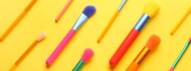 Sarı arka planda renkli makyaj fırçaları. Tasarım için pankart