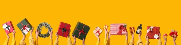Viele Hände Mit Weihnachtsgeschenken Und Dekorationen Auf Gelbem Hintergrund — Stockfoto