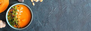 Koyu arkaplanda lezzetli balkabağı kremalı çorba ve metin için yer var.