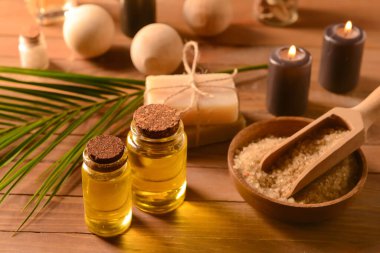 Ahşap zemin üzerinde deniz tuzu bulunan yağ ve kase şişeleri.