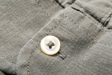 Tarz sahibi gri gömleğin üzerindeki düğmenin yakın görünümü