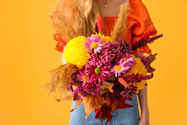 Sarı arka planda güzel bir sonbahar buketi olan kadın, yakın plan.