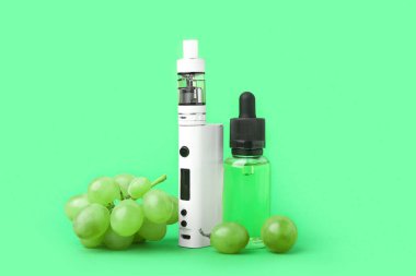 Yeşil zemin üzerinde modern vape mod, yağ ve üzüm
