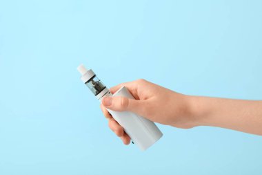 Mavi arka planda modern vape moduna sahip kadın eli