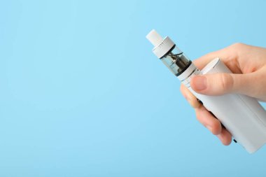 Mavi arka planda modern vape moduna sahip kadın el, yakın plan