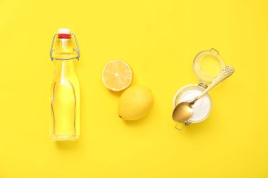 Bir şişe su, olgun limon ve kavanoz sarı arka planda kabartma tozu.