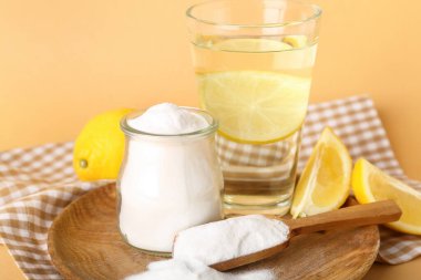Renkli arka planda kabartma tozu, limon ve bir bardak su, yakın plan.