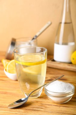 Bir bardak limonlu su ve ahşap masada kabartma tozu.