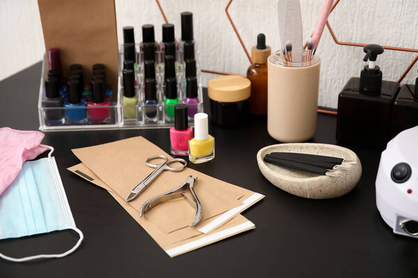 Different manicure instruments and nail polishes on table in beauty salon