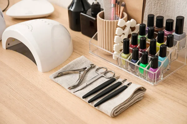 Manicure tools and different nail polishes on wooden table in beauty salon, closeup