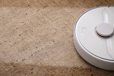 Modern robot süpürgesi yumuşak halıda, yakın plan.