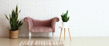 Beyaz tuğlalı duvarın yanındaki ev bitkileriyle lüks bir dinlenme odası.