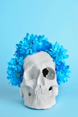 Mavi arka planda çiçekli insan kafatası