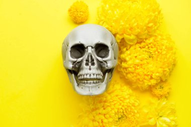 Sarı arka planda çiçekli insan kafatası