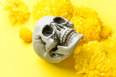 Sarı arka planda çiçekli insan kafatası, yakın plan.